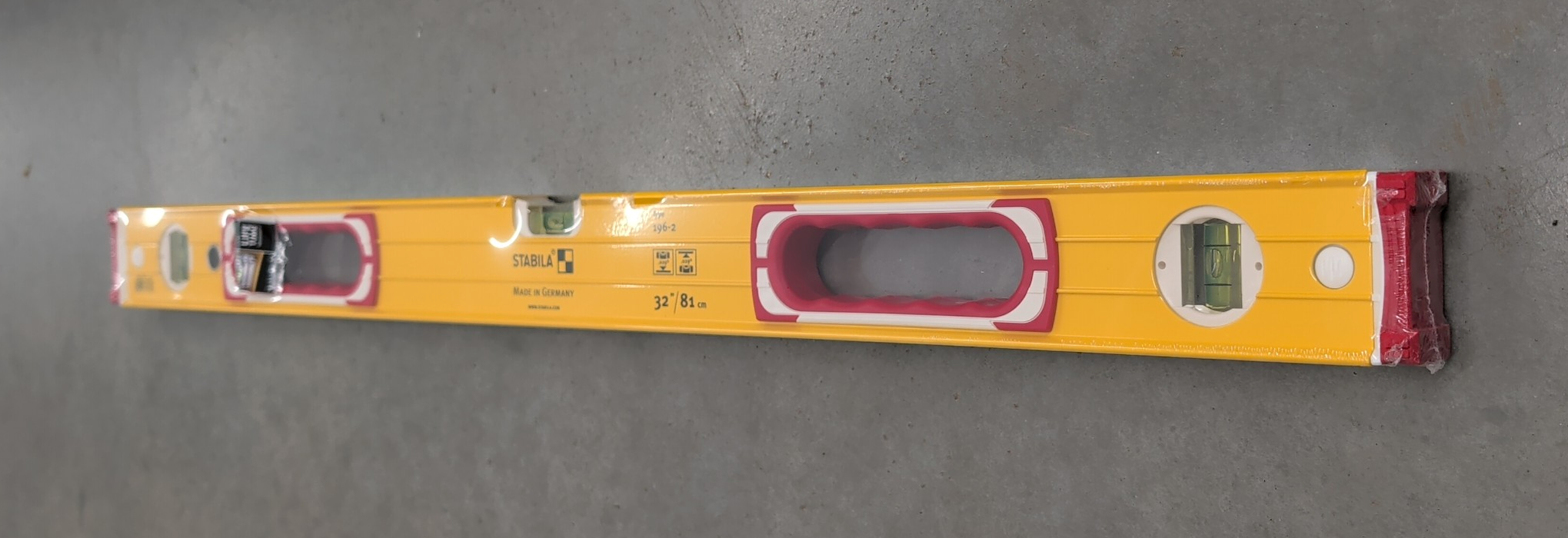 A 32-inch Stabila Type 196-2 yellow aluminum spirit level with red end caps, a central handle, and three vials, wrapped in clear protective film.